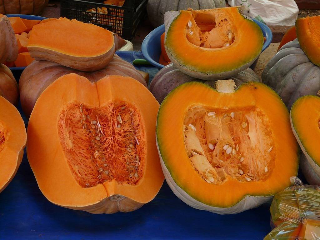 Two halves of a pumpkin showing the inside with seeds visible.